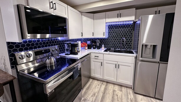 A modern kitchen with stainless steel appliances, white cabinets, and a blue-tiled backsplash. - Extra large 1 Bedroom apartment! (Salem)