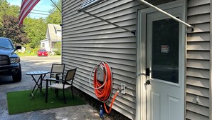 A house with a security camera, a hose, and a flag. - Extra large 1 Bedroom apartment! (Salem)