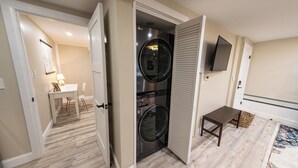 A laundry room with a washer and dryer, a small table, and a TV mounted on the wall. - Extra large 1 Bedroom apartment! (Salem)