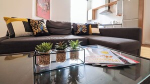 A modern living room with a glass coffee table, a sofa with decorative pillows, and a magazine. - Huge London 2 Bed Flat w/Parking (Greater London)