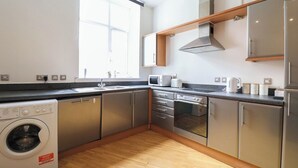 A modern kitchen with stainless steel appliances, wooden flooring, and a built-in washing machine. - Huge London 2 Bed Flat w/Parking (Greater London)