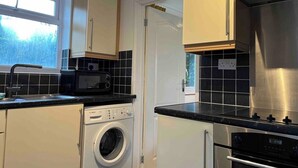 A compact kitchen with a washing machine, microwave, and dishwasher.