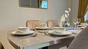 A dining table set with white plates, bowls, and wine glasses, with a vase of flowers on the table.