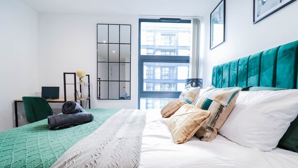Una habitación de hotel con cama, escritorio, silla y ventana con vista a la ciudad.