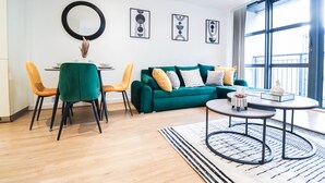 Una sala de estar moderna con un sofá verde, sillas amarillas, una mesa de comedor y un ventanal grande.