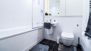 Un baño moderno con bañera, lavamanos e inodoro.