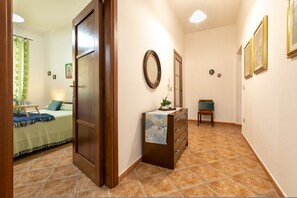 A hotel room with a bed, a dresser, a mirror, and a small table with a plant. - Sardinia RE - Al Porto (Alghero)