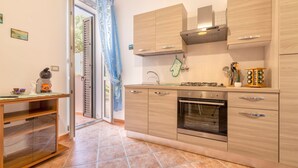 A modern kitchen with wooden cabinets, a gas stove, an oven, and a sink. - Sardinia RE - Al Porto (Alghero)