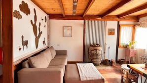 Ein gemütliches Wohnzimmer mit Holzbalkendecke, einem Ecksofa und rustikalem Dekor.