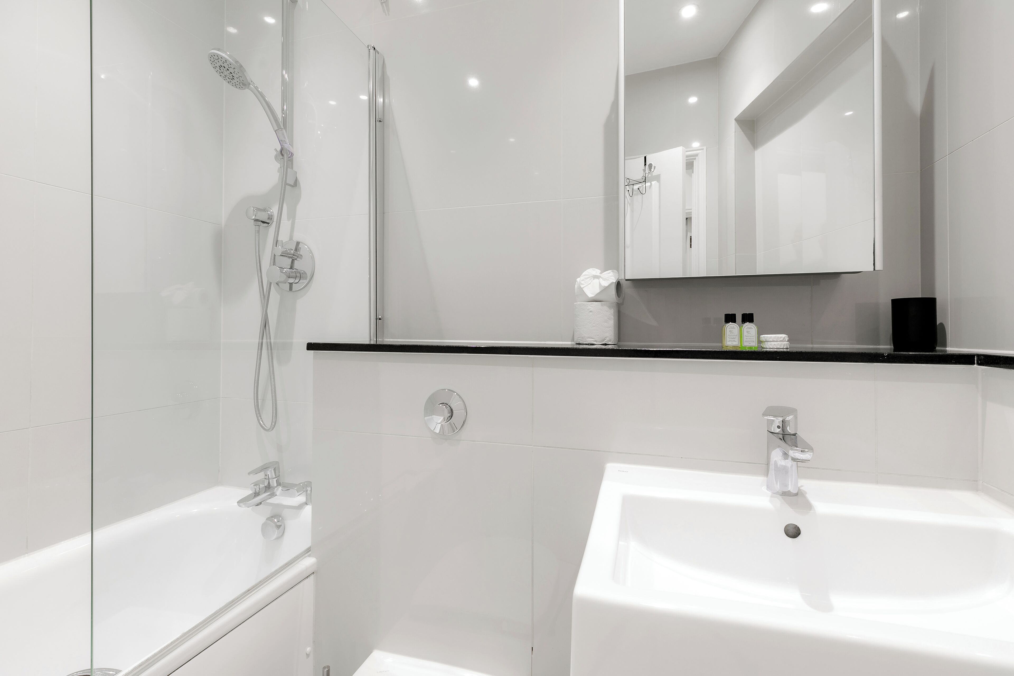 A modern bathroom with a glass-enclosed shower, a white sink, and a large mirror.