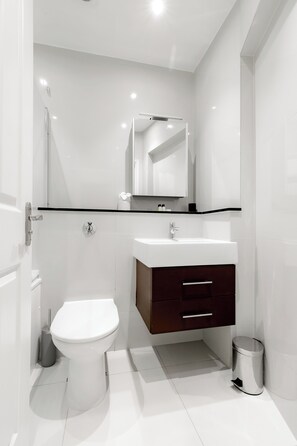A modern bathroom with a white toilet, a sink, and a mirror above it. - Marylebone by Excel Apartments (London)