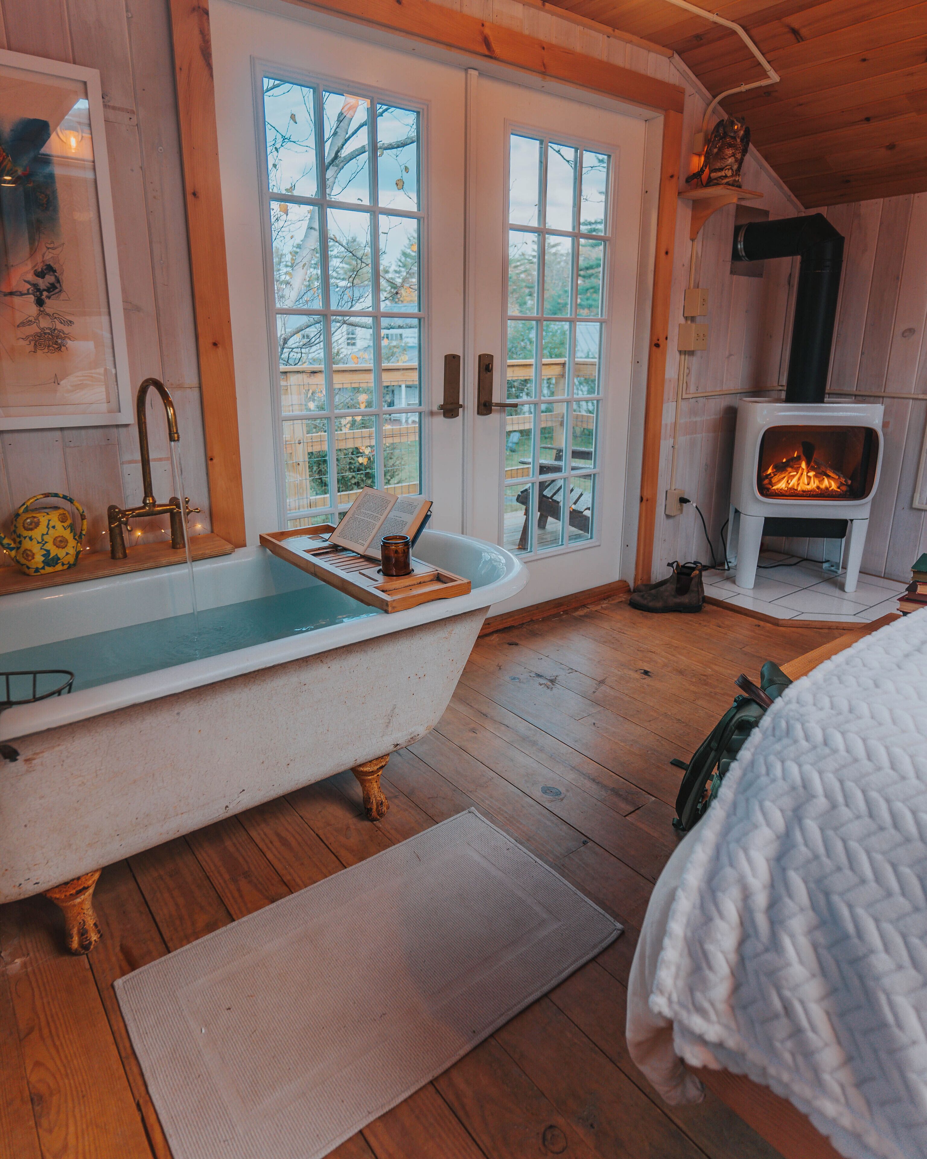 A room with a bathtub, a fireplace, and a view of the outdoors.