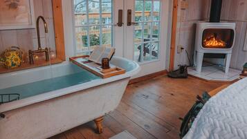 A room with a bathtub, a fireplace, and a view of the outdoors.