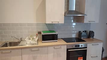 Una cocina moderna con un lavamanos de acero inoxidable, un microondas, un horno y una campana extractora.