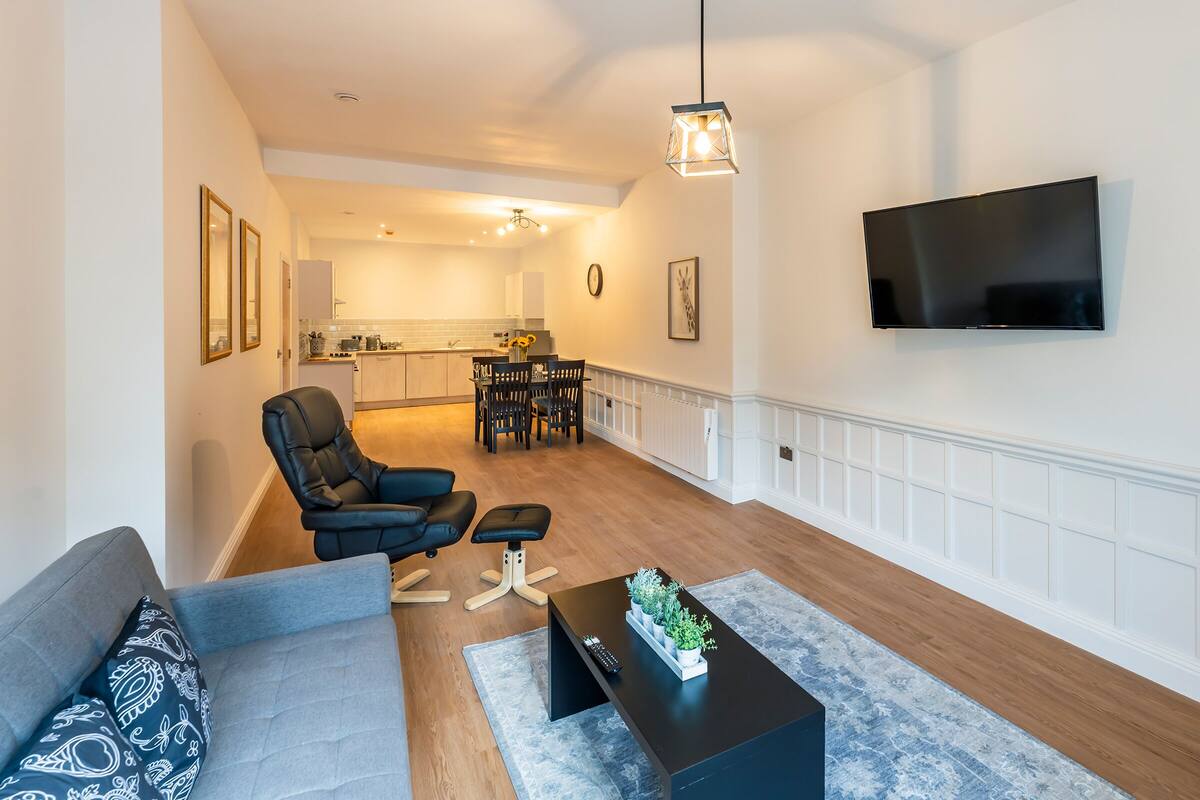 A modern living room with a sofa, a coffee table, and a TV mounted on the wall.