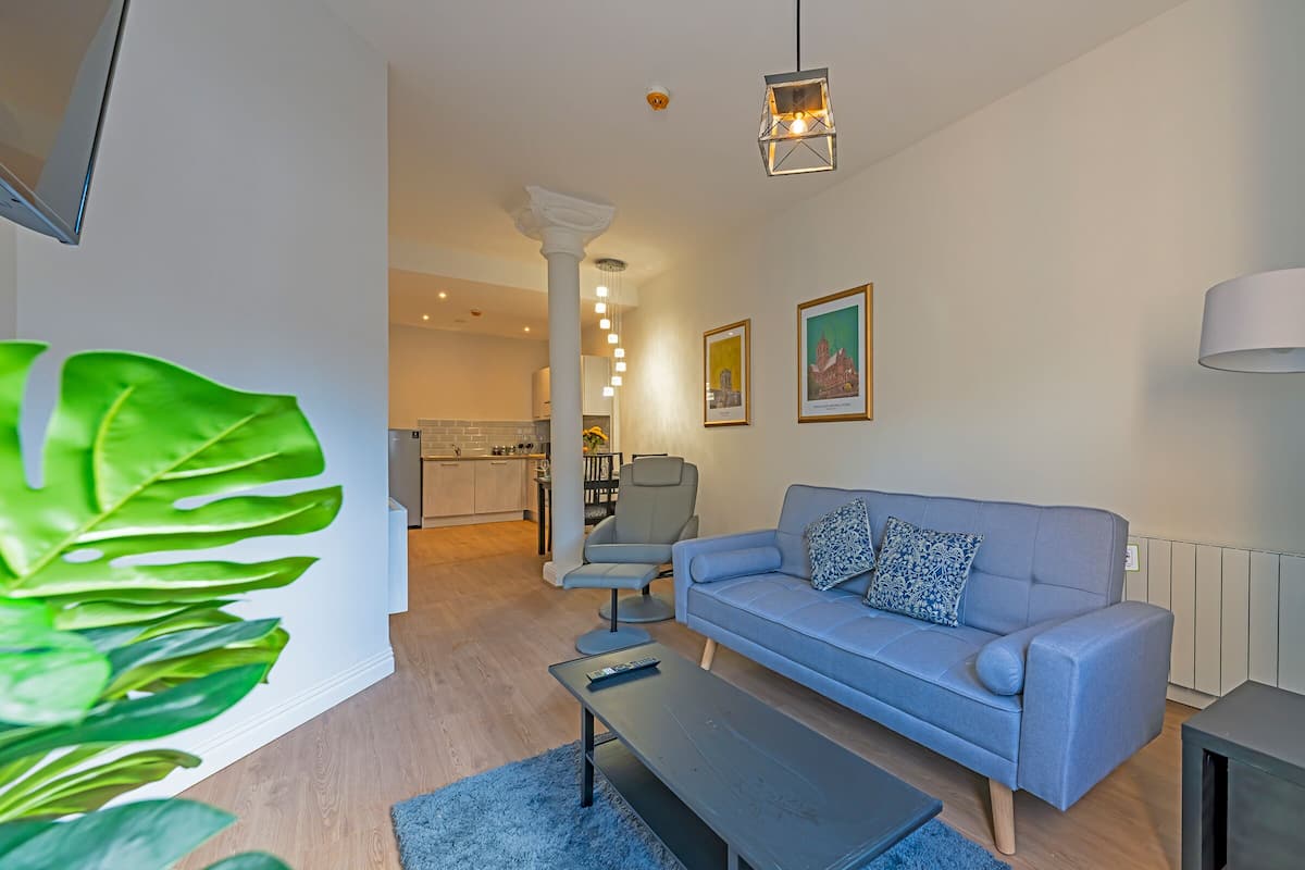 A modern living room with a grey sofa, a coffee table, and a large green plant.