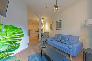 Una sala de estar moderna con un sofá gris, una mesa de centro y una planta verde grande.