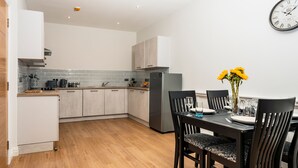 A modern kitchen with white cabinets, a grey tiled backsplash, and a stainless steel refrigerator. - The Hazlitt Apartments (Paisley)