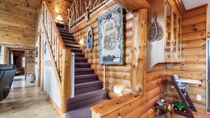 Interno di una baita in legno con una scala in legno, una sala da pranzo e un'area giochi per bambini.