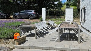 An outdoor seating area with tables and chairs, a stone pathway, and a parked car. - Domein le Crupet 30 Personen Gelegen op Domein Van3 ha (Hastière)