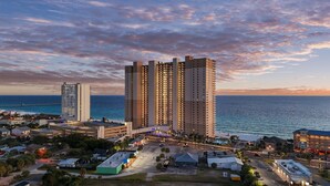 A high-rise hotel with multiple floors, a view of the ocean, and a pier in the background. - Beachfront 4BR | Heated Pool + Hot Tub (Panama City Beach)