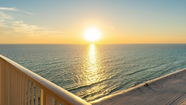 A sunset over the ocean with a beach and a wooden railing. - Beachfront 4BR | Heated Pool + Hot Tub (Panama City Beach)