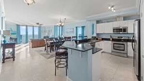 A spacious kitchen with a central island, modern appliances, and a dining area with a view. - Beachfront 4BR | Heated Pool + Hot Tub (Panama City Beach)