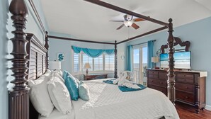 A four-poster bed with a ceiling fan, a TV, and a view of the ocean. - Beachfront 4BR | Heated Pool + Hot Tub (Panama City Beach)