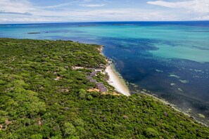 An aerial view of a coastal area with dense greenery, a sandy beach, and clear turquoise waters. - Tao Resort Madagascar (Antsiranana)