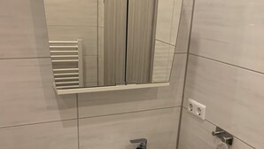 A bathroom with a white sink, a mirror, and a towel rack. - Apartments Mitte Messe und Zentrum (Nürnberg)