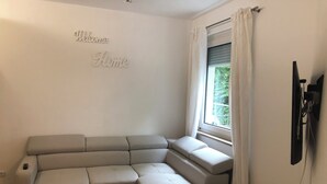 A modern living room with a sectional sofa, a wooden coffee table, and a 'Welcome Home' sign on the wall. - Apartments Mitte Messe und Zentrum (Nürnberg)