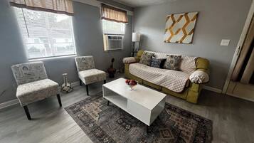 Un salon comprenant un canapé, des fauteuils, une table basse et un tapis à motifs.