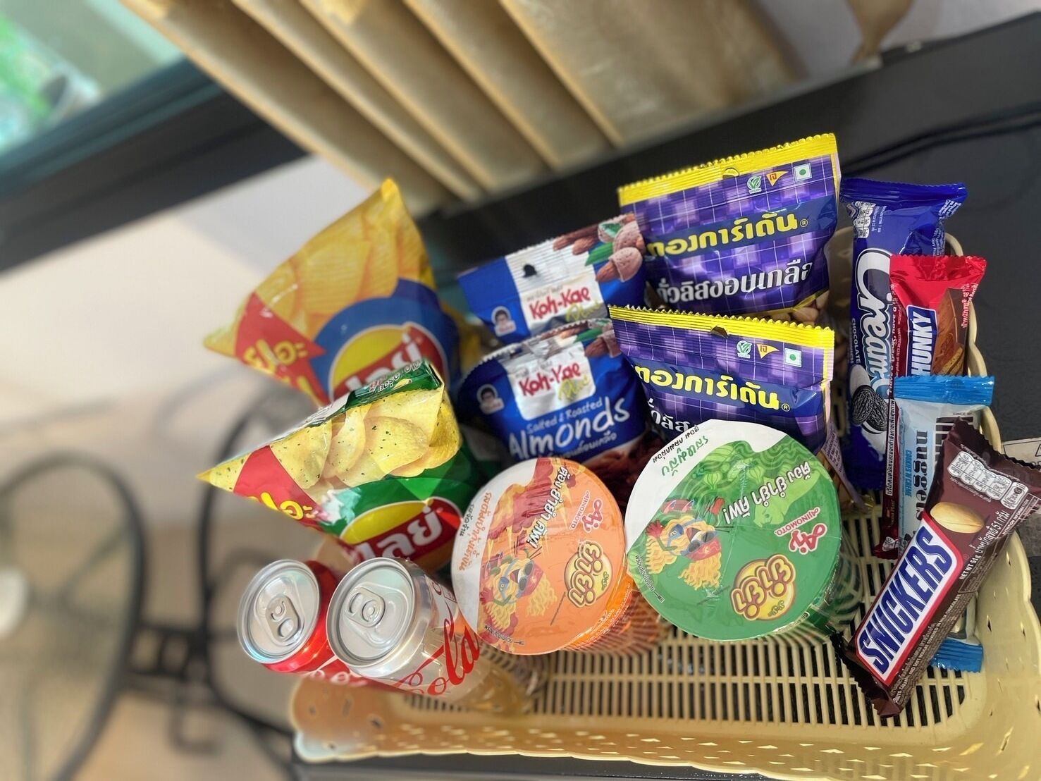 A basket filled with snacks including chips, almonds, and chocolate bars.