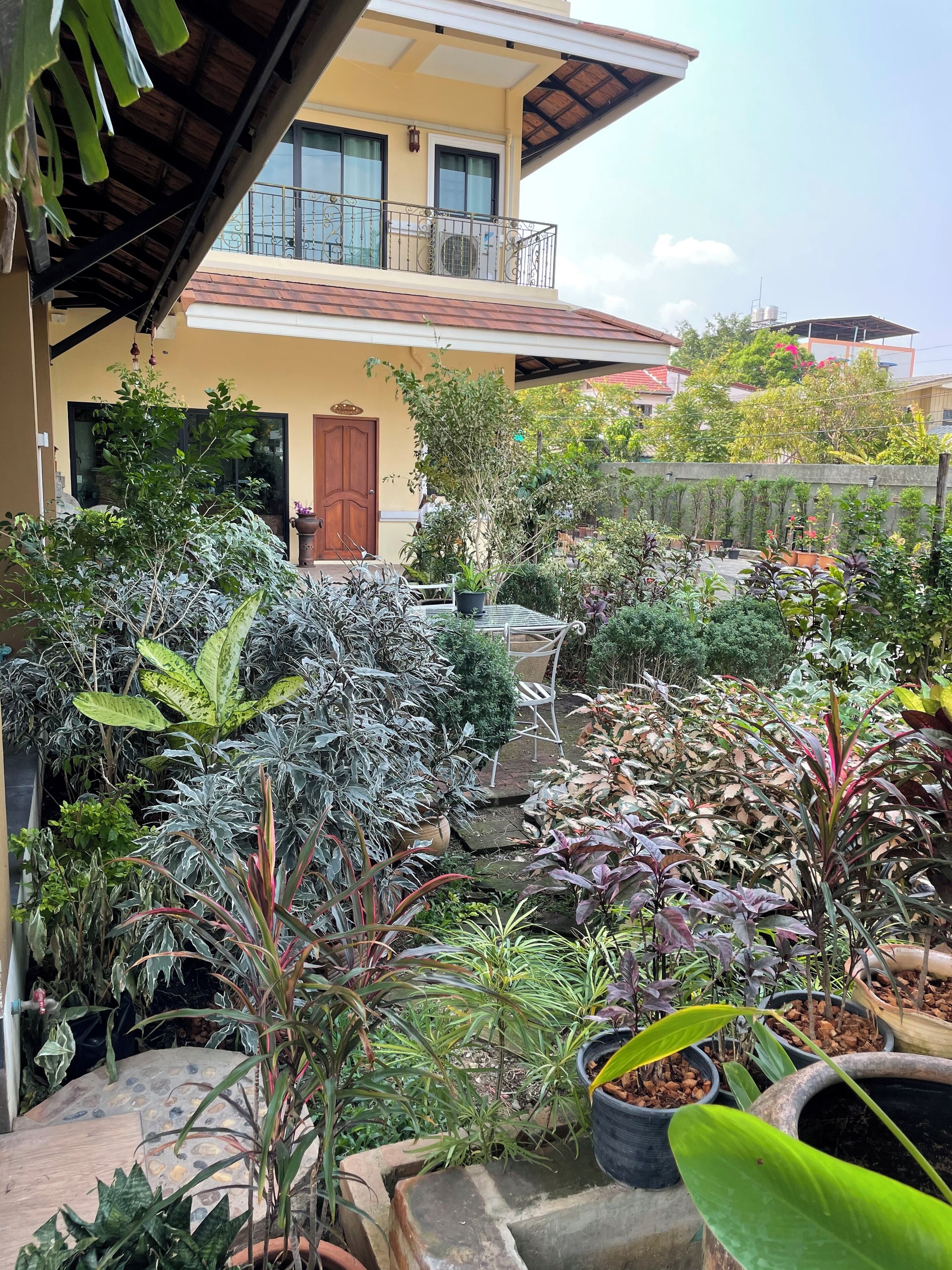 A residential building with a balcony, potted plants, and a small outdoor seating area.