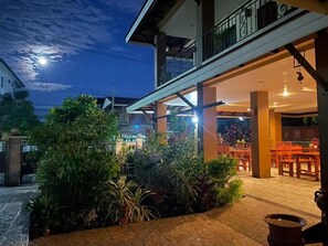 A restaurant with outdoor seating, a balcony, and a well-lit entrance. - Laph Kham House (Chiang Mai)