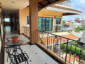 A balcony with a potted plant and chairs, a view of the neighborhood, and a dog lying on the floor. - Laph Kham House (Chiang Mai)