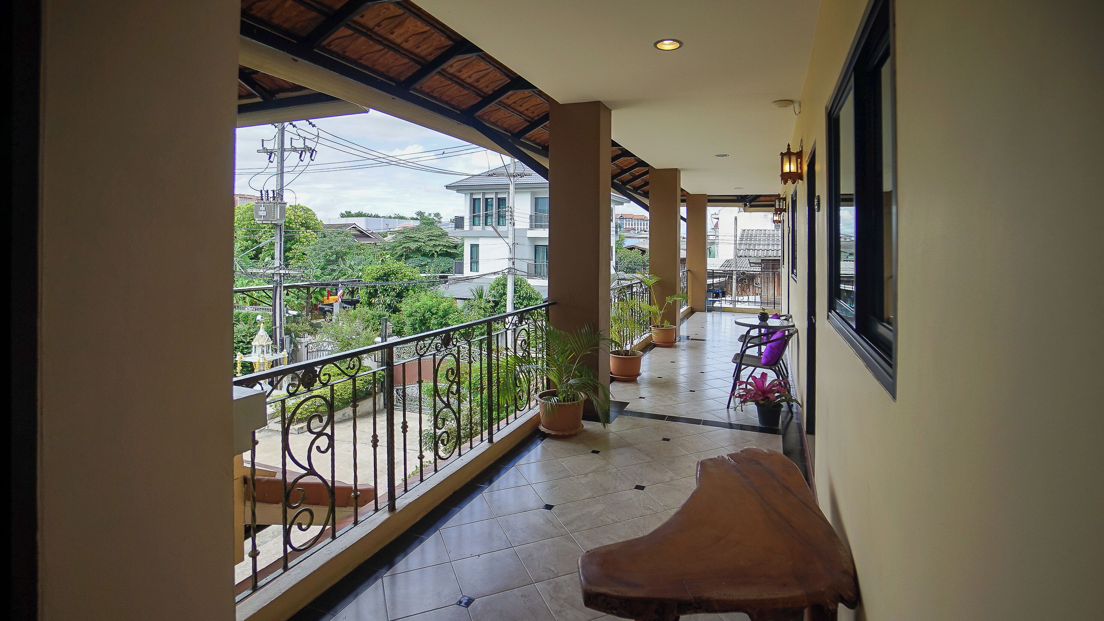 A corridor with a balcony, potted plants, and a table.