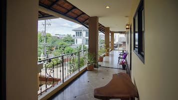 A corridor with a balcony, potted plants, and a table.