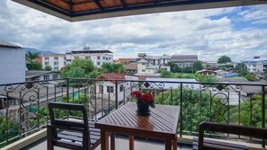A balcony with a table and chairs, overlooking a residential area with various buildings and greenery. - Laph Kham House (Chiang Mai)