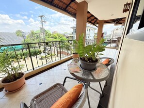 A balcony with a table, chairs, potted plants, and a view of the surrounding neighborhood. - Laph Kham House (Chiang Mai)