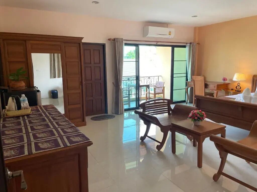 Habitación de hotel con escritorio de madera, una mesa de comedor y sillas. Incluye un balcón con vistas al exterior.