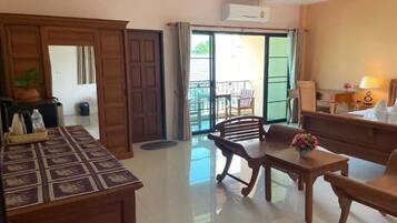Habitación de hotel con escritorio de madera, una mesa de comedor y sillas. Incluye un balcón con vistas al exterior.