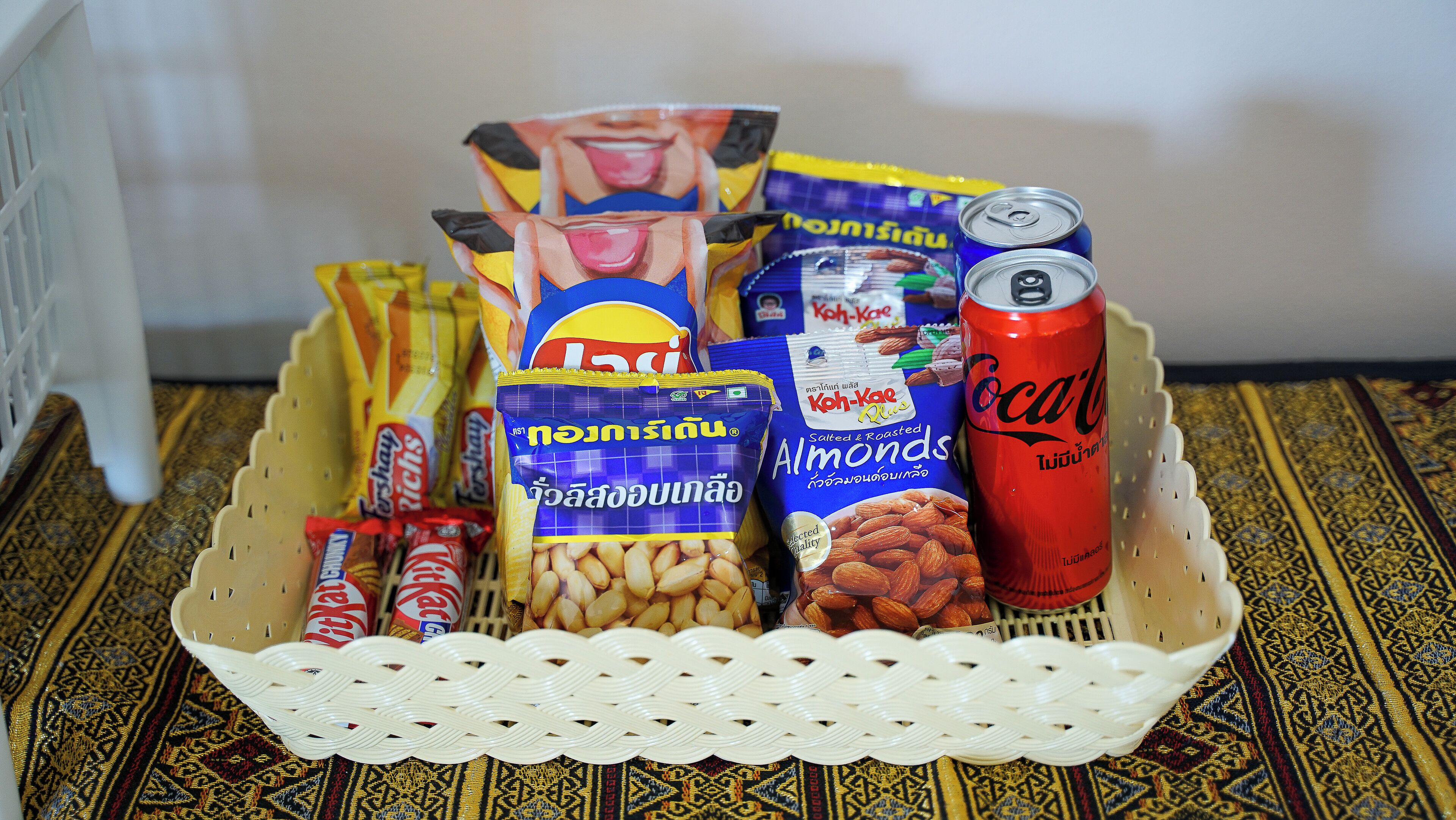 A basket containing snacks, a can of Coca-Cola, and a bag of almonds.