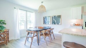 Een eetgedeelte met een ronde tafel, houten stoelen en een hanglamp.