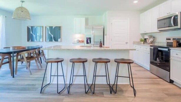 Een moderne keuken met een centraal eiland, barstoelen en een eettafel.