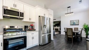 A modern kitchen with white cabinets, stainless steel appliances, and a dining area with a table and chairs.
