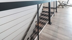 Un interior moderno con una escalera, un cuadro en la pared y una mesa de conferencias al fondo.
