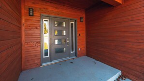 Fachada de madera con una puerta gris y un pequeño porche.