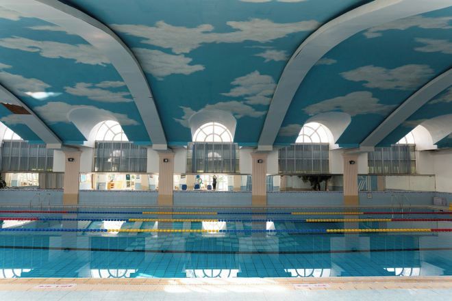 Una piscina interior con techos altos y ventanas arqueadas.