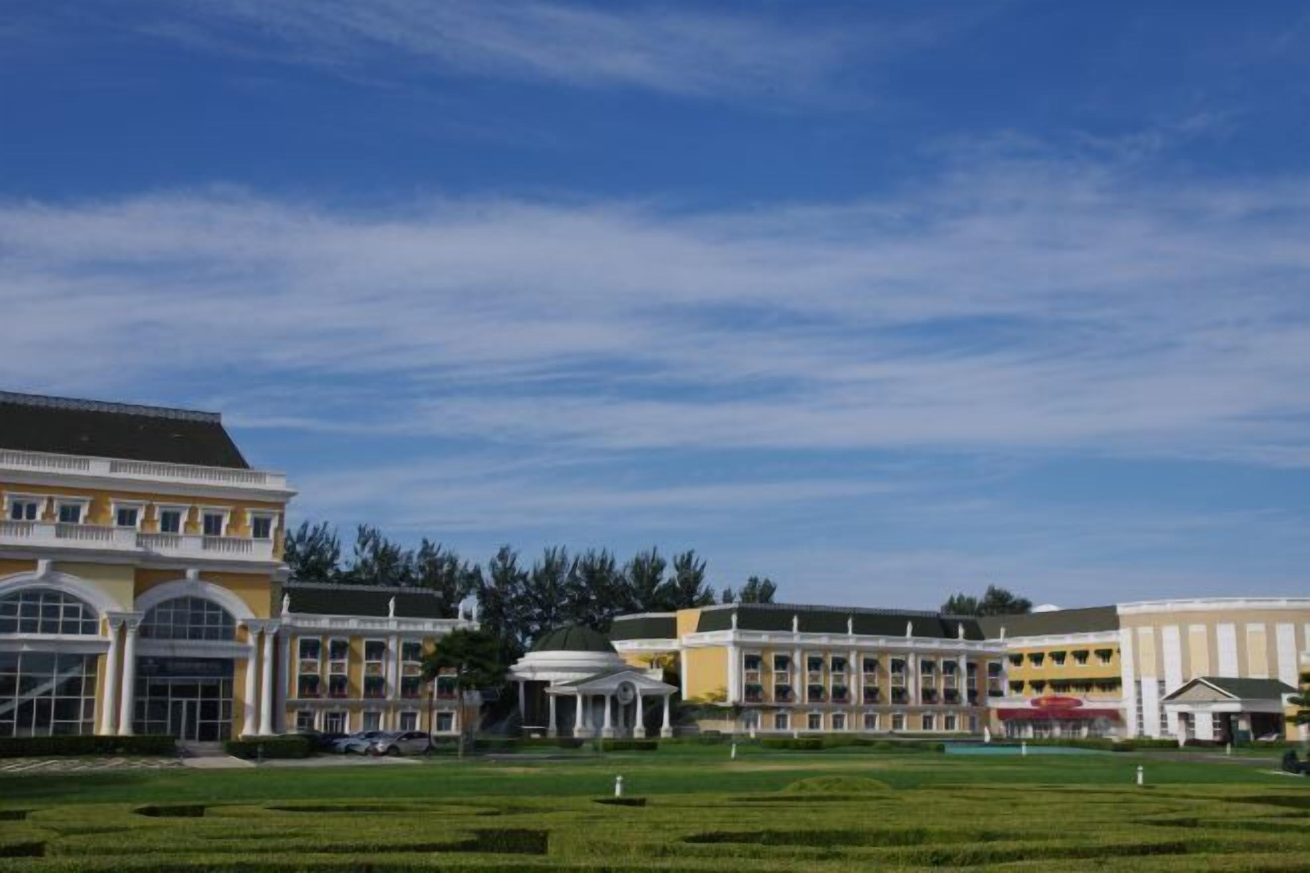 Um grande hotel com vários edifícios, uma cúpula central e um jardim bem cuidado.